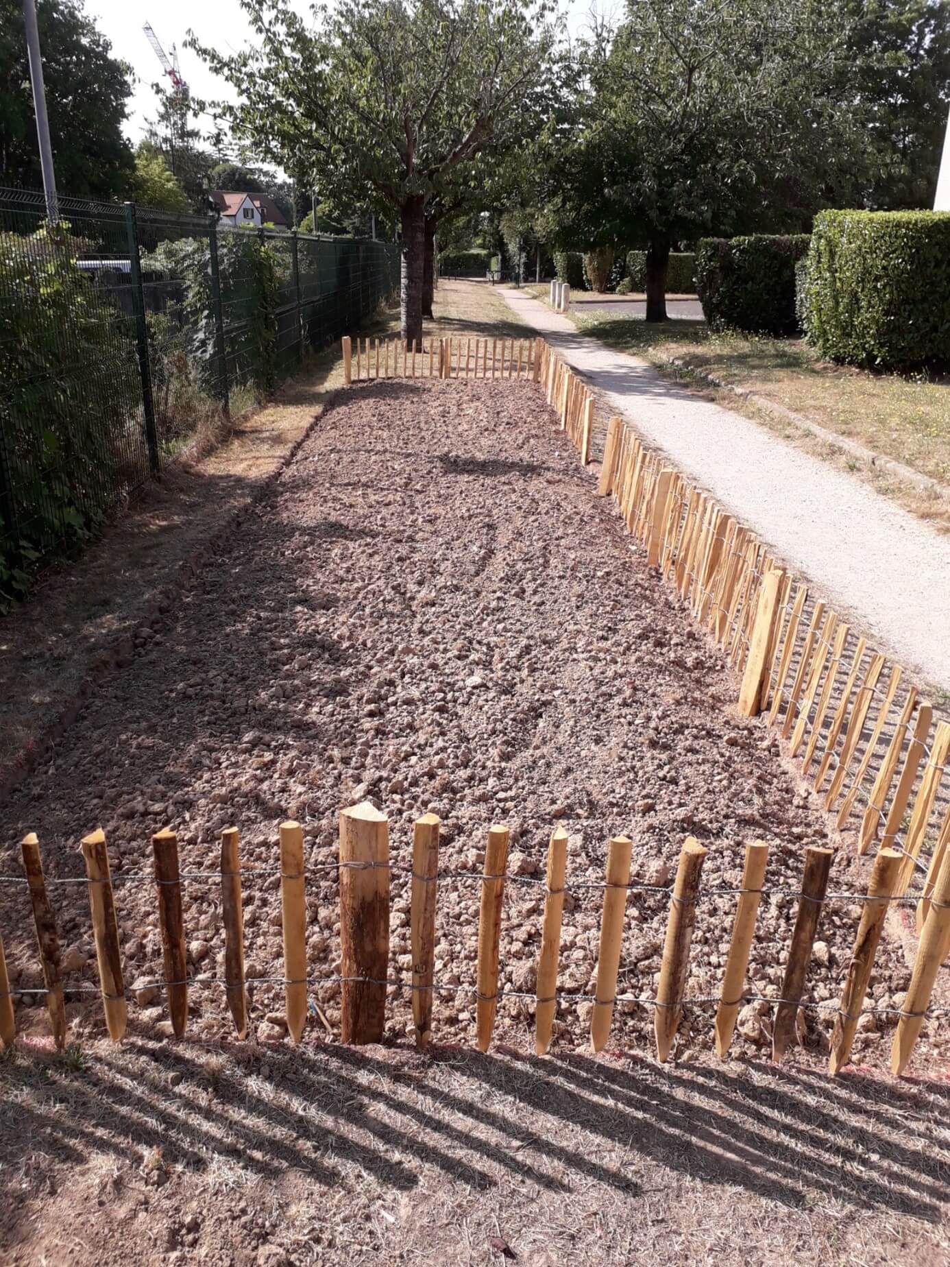 Petit terrain entouré de barrière en bois contenant pour l'instant des gravillon car le projet est en cours de réalisation